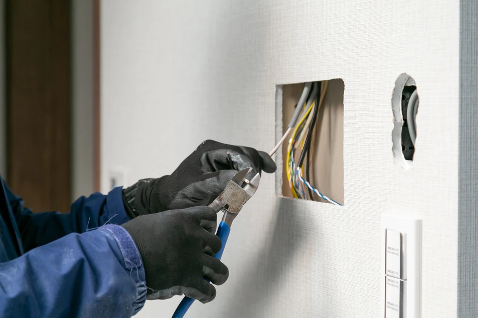 Scène d'intérieur montrant une prise électrique murale défaillante avec flammes visibles et fumée